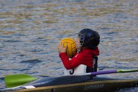 Kind mit Ball im Kanu-Polo Boot